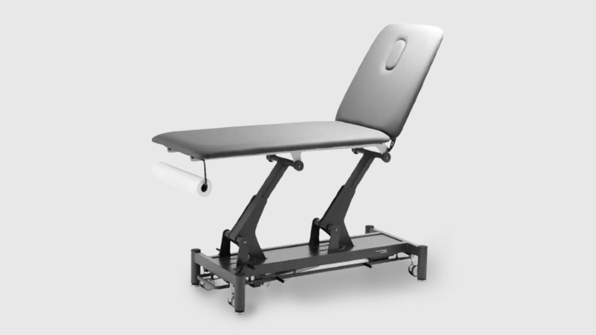 Une table de kinésithérapie électrique, à deux plans, avec un châssis noir et un revêtement gris foncé, dotée d'un rouleau de papier d'examen au niveau des pieds. La table est présentée dans un environnement de cabinet médical ou de massothérapie moderne et épuré, prête à l'emploi